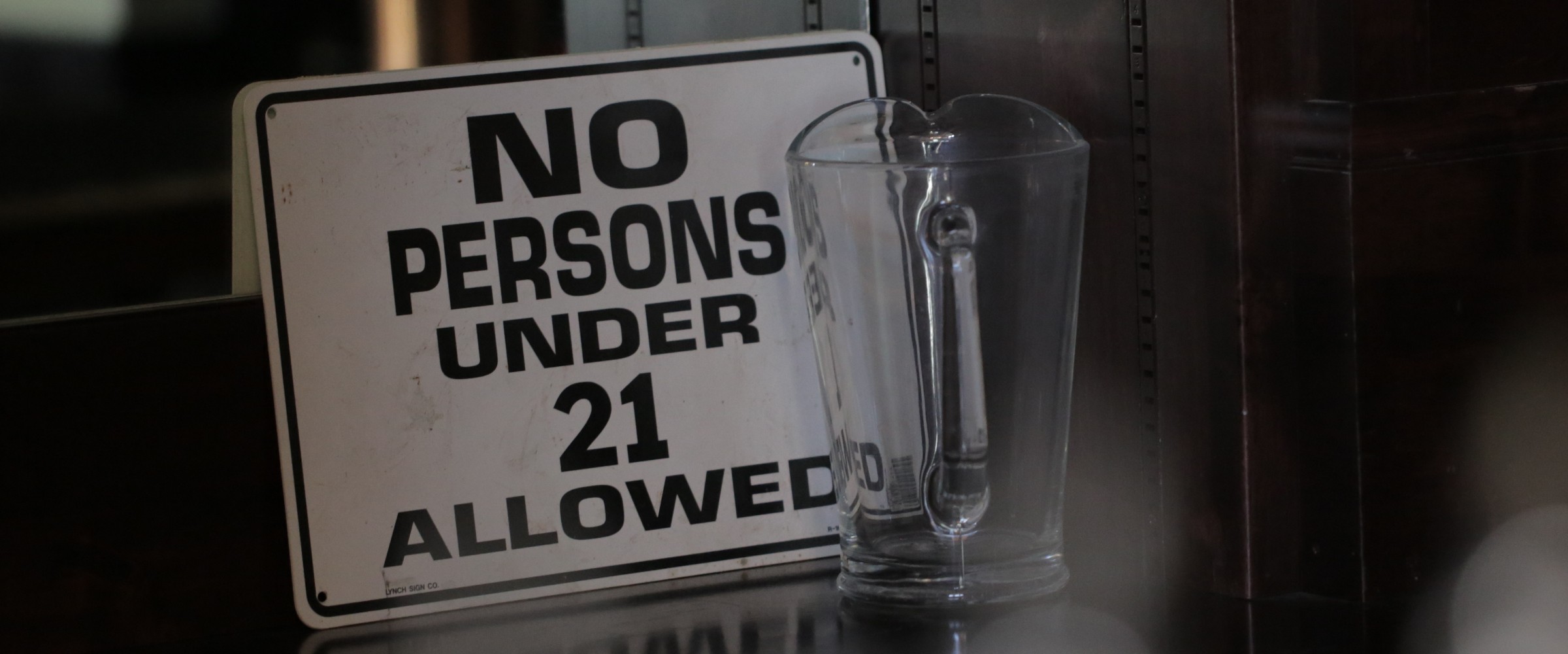 A weathered &lsquo;No persons under 21 allowed&rsquo; bar sign
